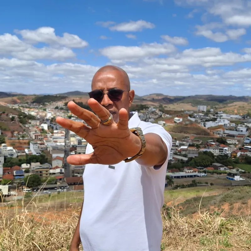 Estevão Maria com a mão estendida, com a cidade ao fundo